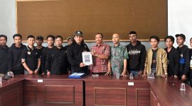 Caption: Hanafi, Ketua Cabang PSHT Sampang Jaket Hitam Saat Menyerahkan Berkas Pembaruan Legalitas Kepada Bambang, Kabid Politik Dalam Negeri Bakesbangpol Kabupaten Sampang