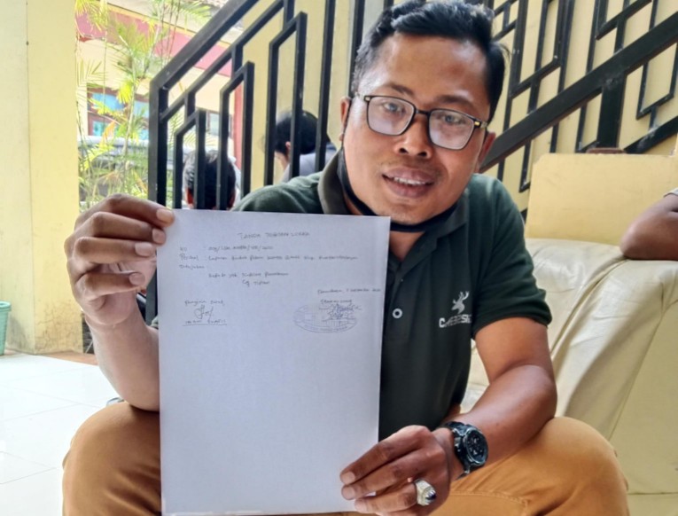 Caption: Ketua LSM AWPM Imam Syafi’i Memegang Bukti Tanda Terima Laporan usai melapor ke Polres Pamekasan, Senin (01/09/2025)