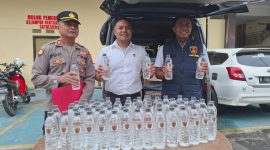 Caption: Kasat Reskrim Polres Sampang, Iptu Nur Fajri Alim, di Tengah Menggunakan Baju Putih Memperlihatkan Botol Miras Arak Bali (Sumber Foto: Humas Polres Sampang/dok Pilar Pos)